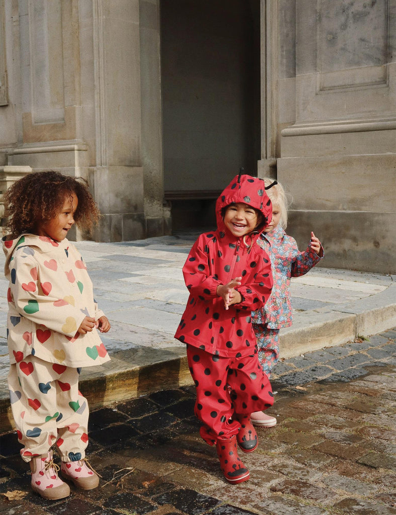 Image of a child wearing a matching hooded jacket and pant rain set. 