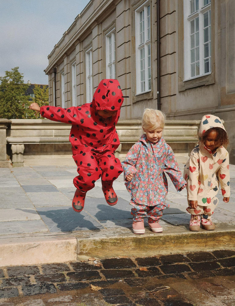 Image of a child wearing a matching hooded jacket and pant rain set. 