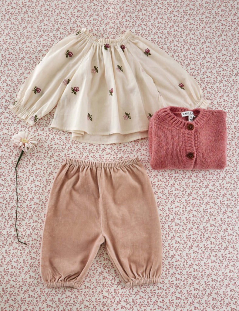 Children's outfit with top, pants, and sweater on a floral background