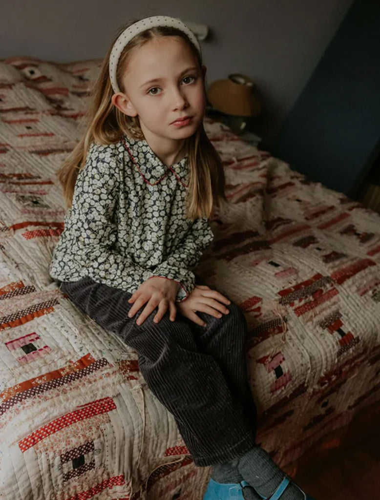 Young girl sitting on a patterned bedspread