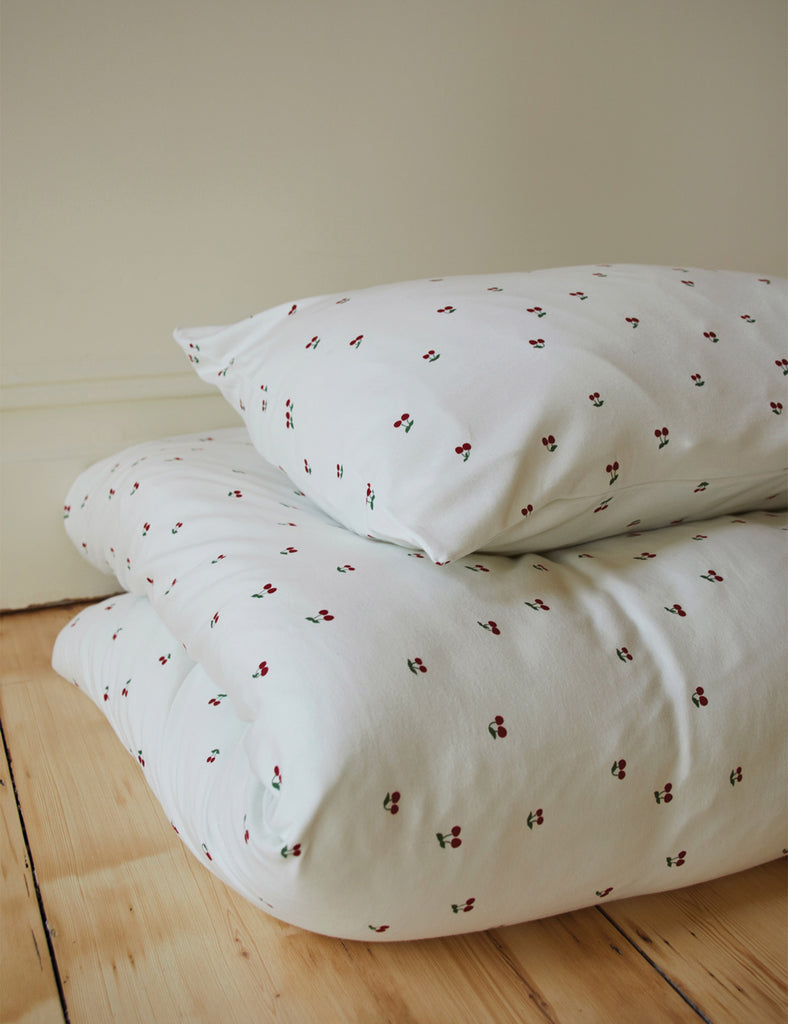 White pillowcases with small red patterns on a wooden surface