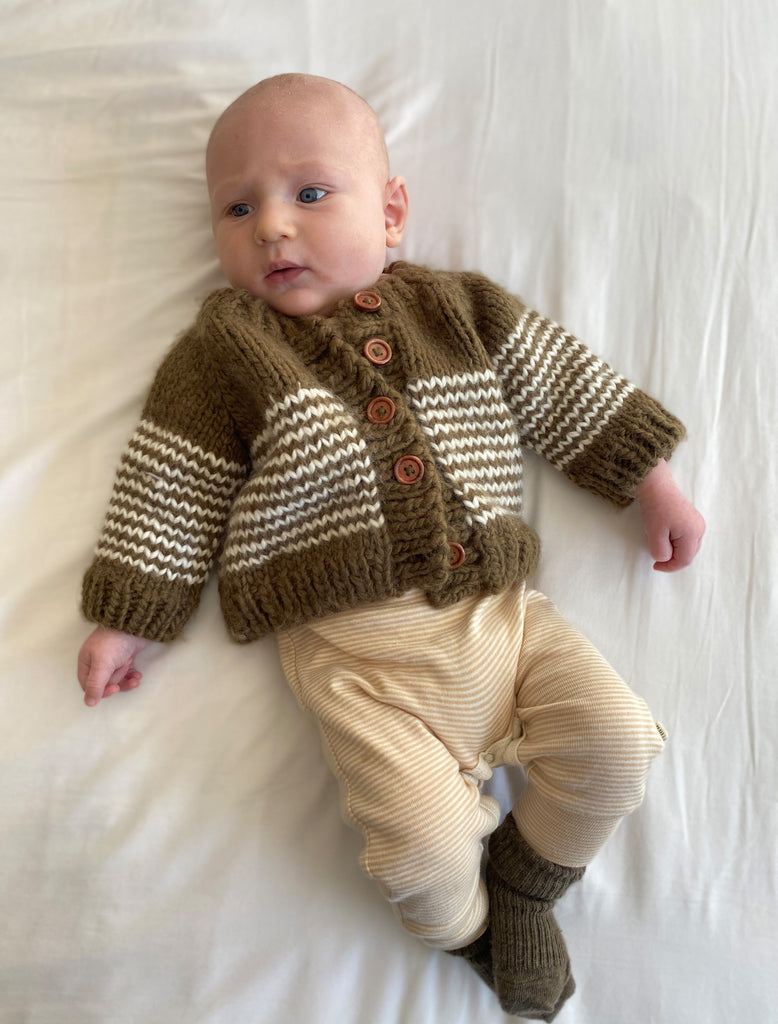 Cocoa striped cardigan on baby laying down.