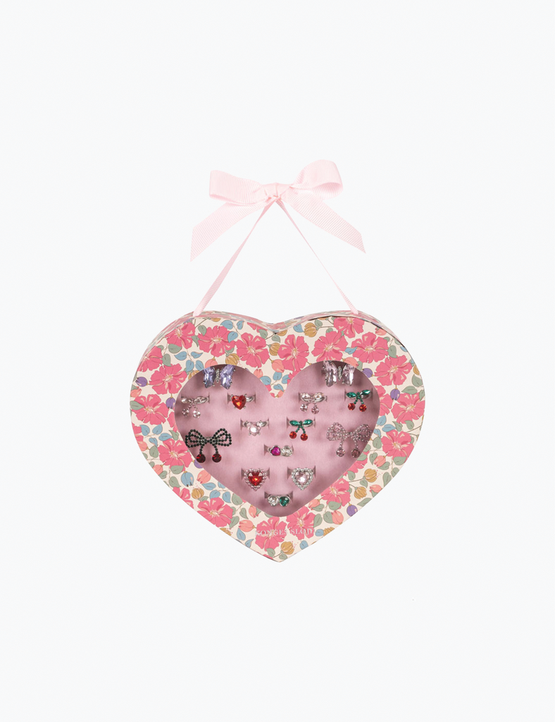 Heart-shaped floral display with jewelry on a white background