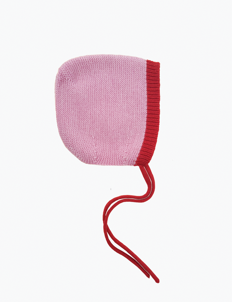 Knitted baby bonnet with pink top and red bottom on a white background