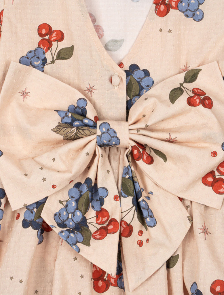 Close-up of a fabric with a bow and berry pattern on a beige background