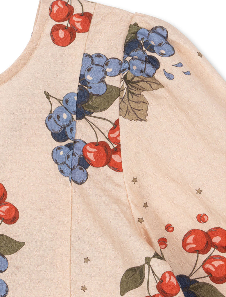 Close-up of a fabric with cherry and blueberry pattern on a beige background