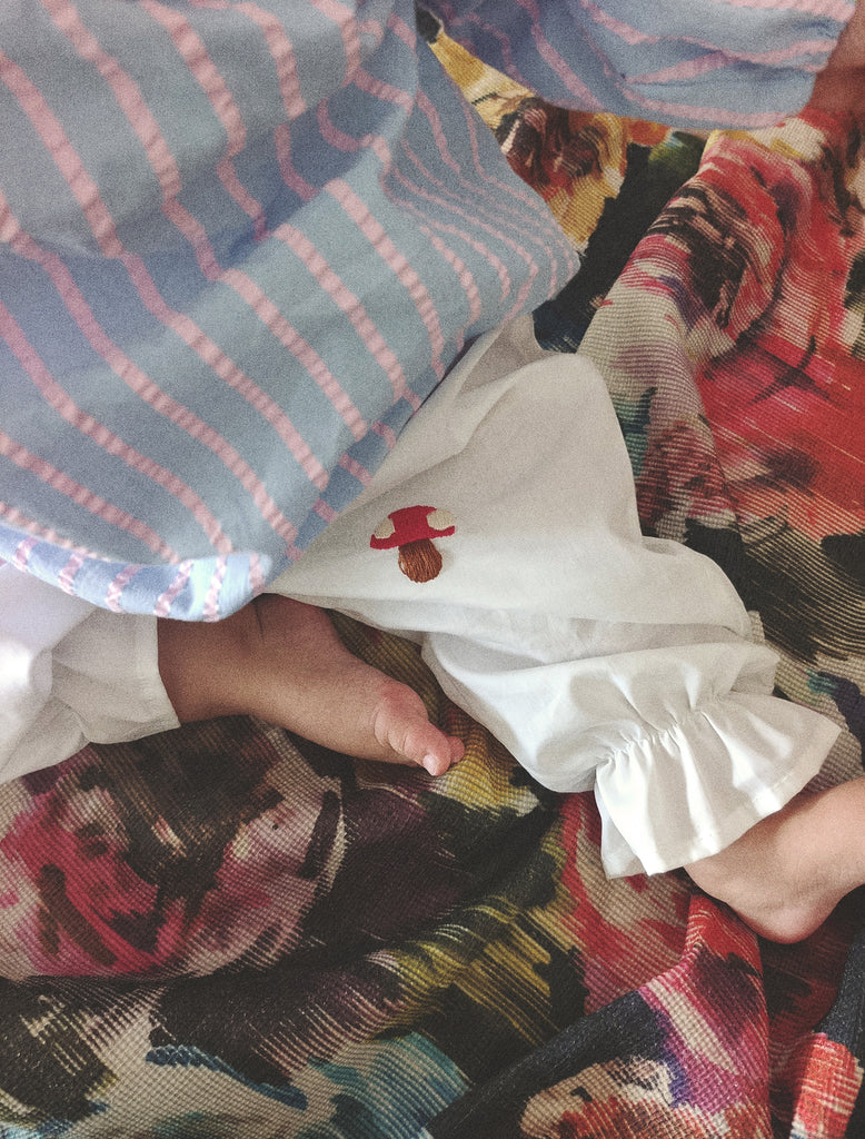 Close-up of a child's feet in white socks with red patterns on a colorful rug.