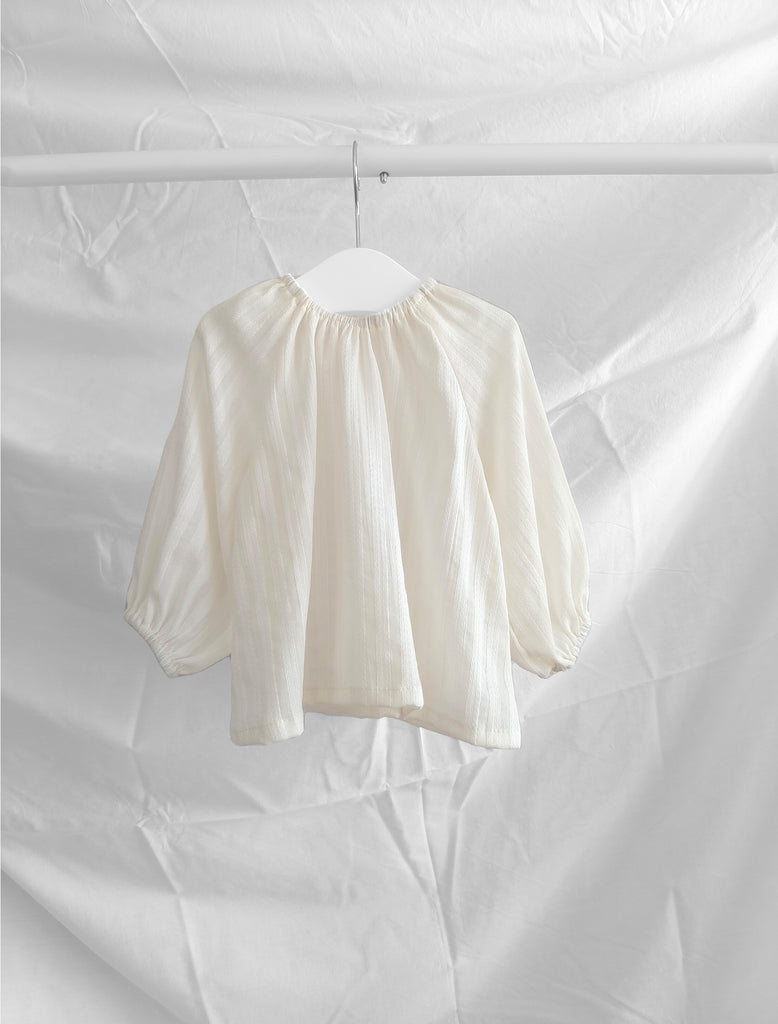 White blouse on a hanger against a white background
