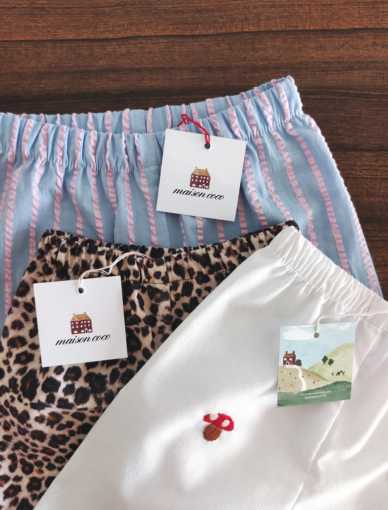 Three pairs of pants with tags on a wooden surface