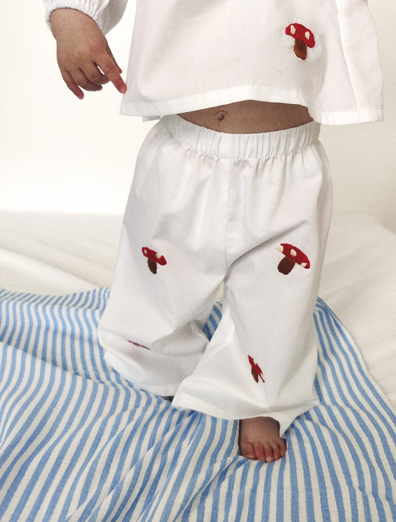 White blouse and pants with red mushroom designs on a striped fabric background
