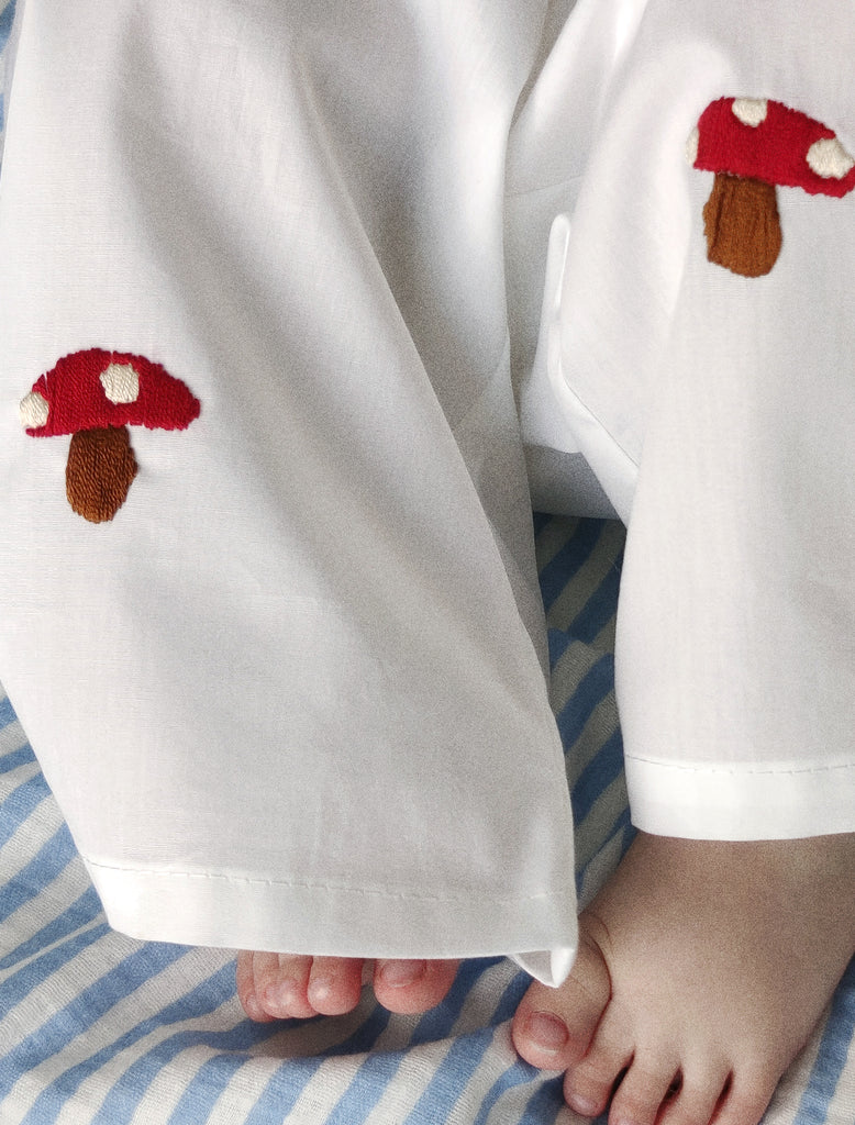 White pants with mushroom designs on a striped fabric background