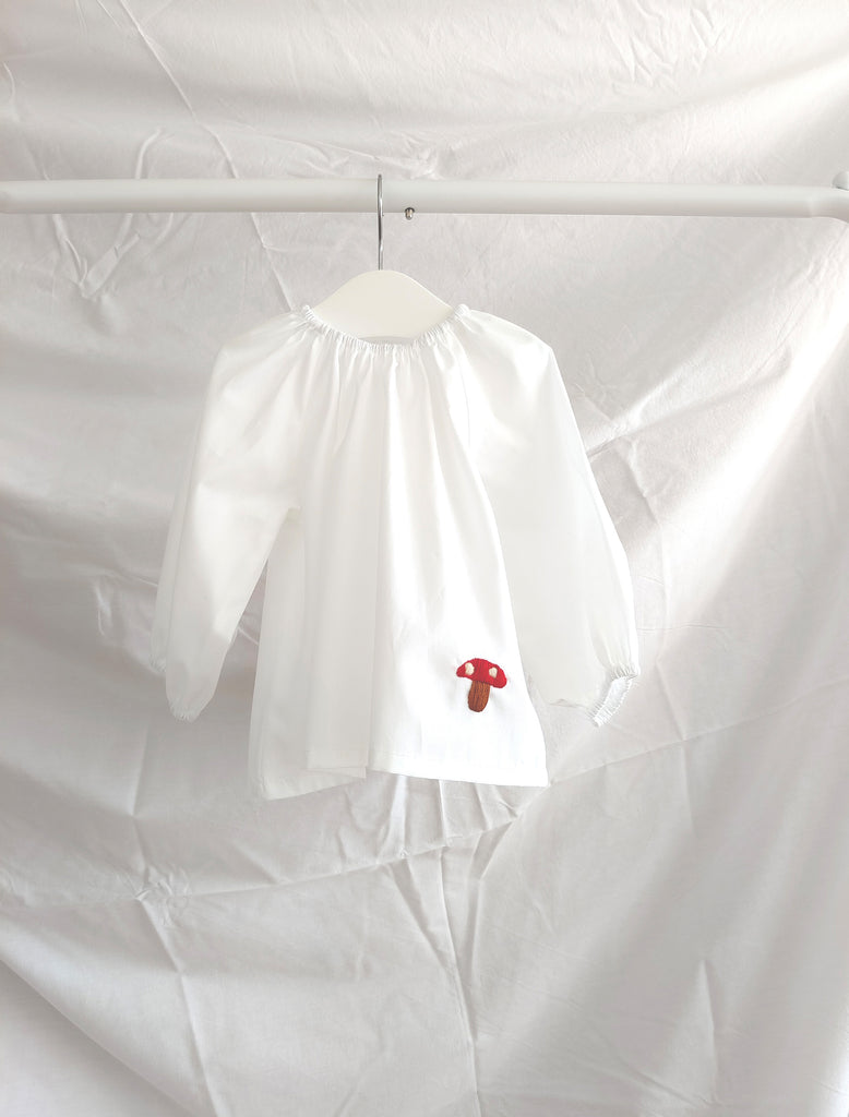 White shirt with a red logo on a hanger against a white background