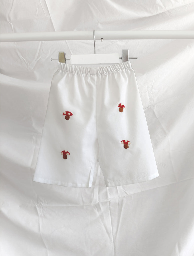 White pants with red mushroom embroidery on a white background