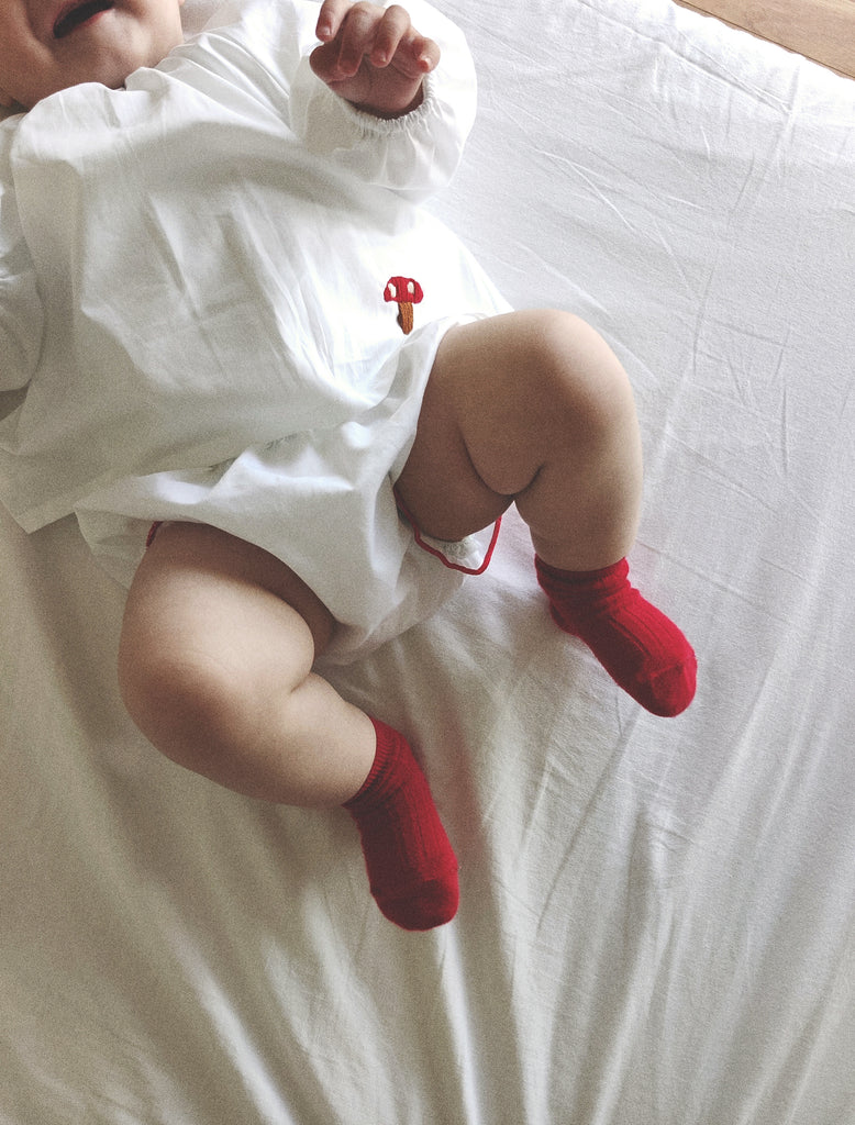 Baby wearing red socks on a white surface