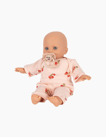 Baby doll wearing a pink outfit with floral patterns on a white background
