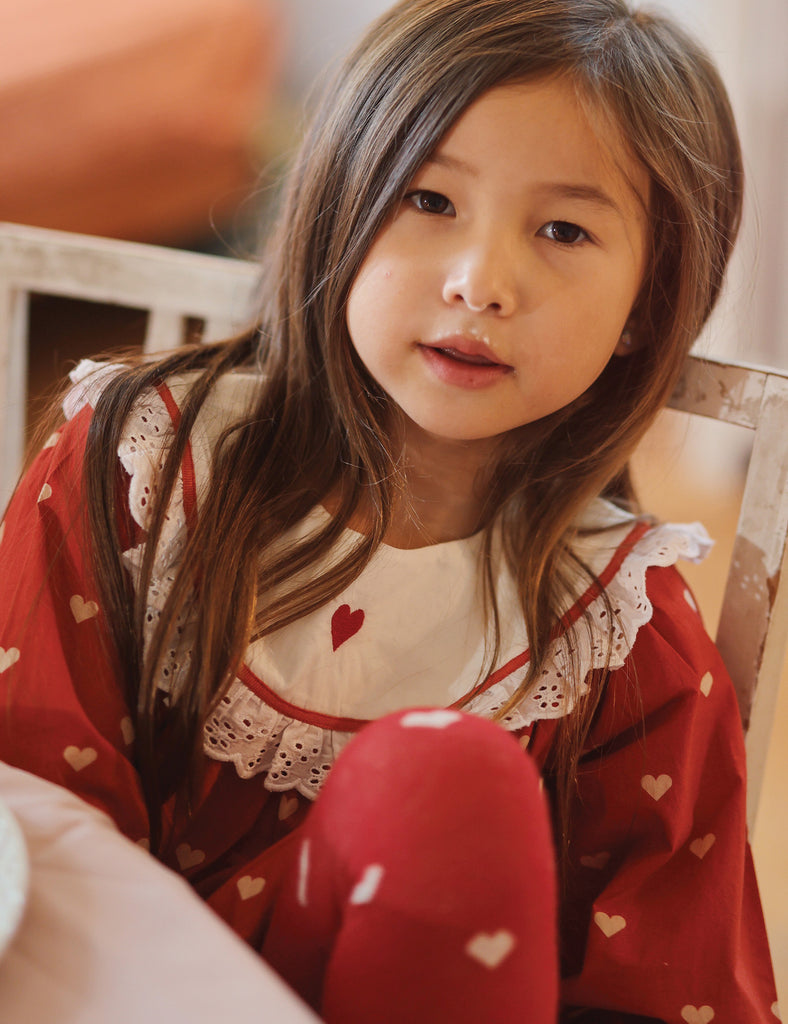 Young girl wearing a red outfit with heart patterns indoors
