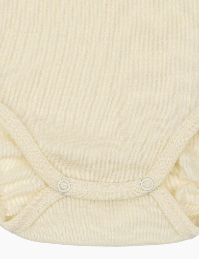 Close-up of a cream-colored baby bodysuit with snaps on a white background
