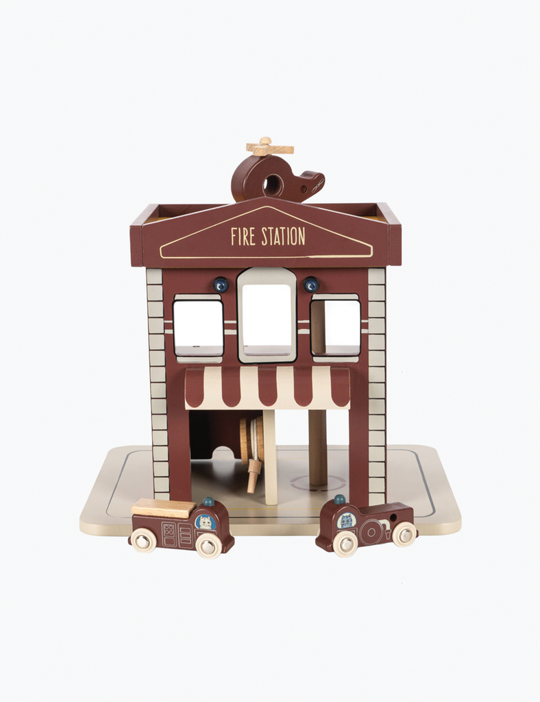Wooden toy fire station with two fire trucks on a white background
