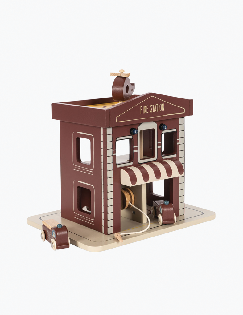 Wooden toy fire station with moving parts on a white background
