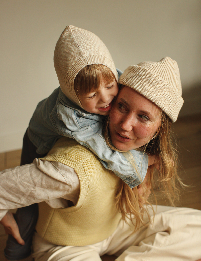 Woman and child wearing matching beige hats in a warm setting