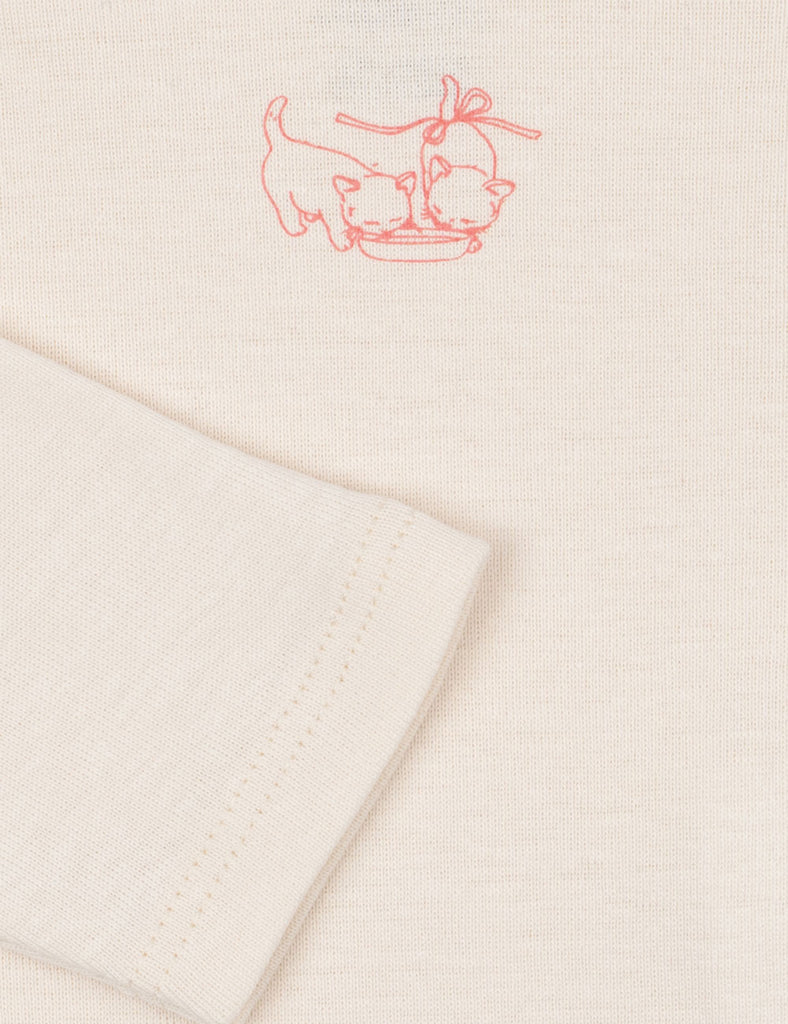 Close up of the kittens sipping from a plate on a baby bodysuit.