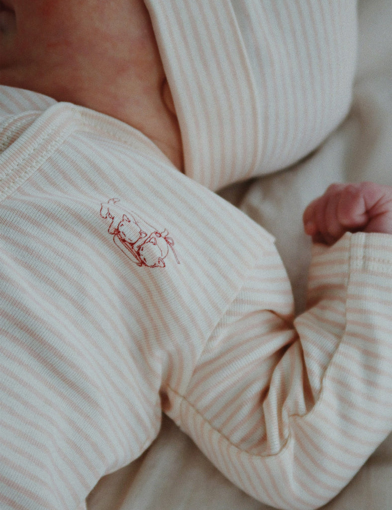 Close-up of a baby in striped pajamas with a small embroidered design on the chest.