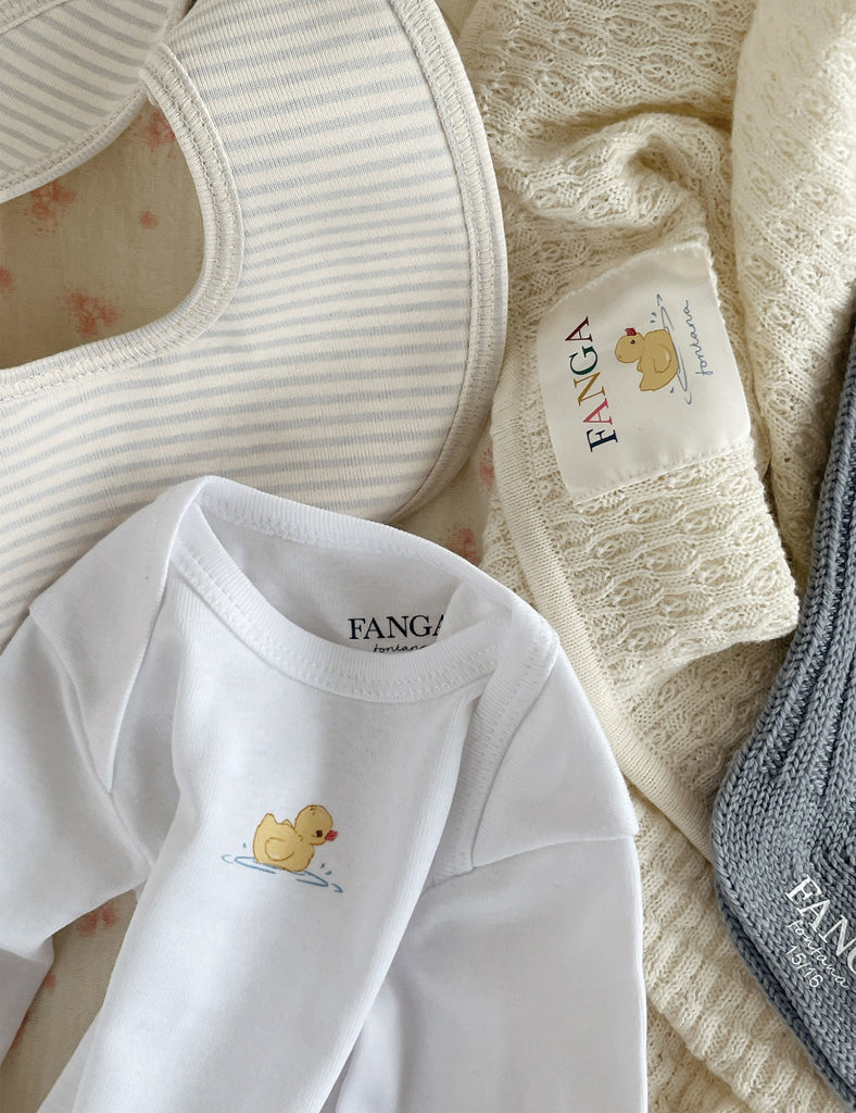 Baby clothing and accessories with 'FANGA' branding on a textured surface