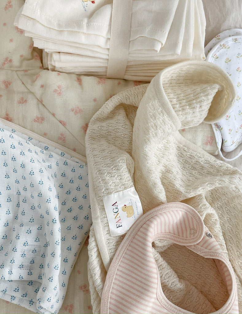Stack of baby blankets with floral patterns and a visible brand label.