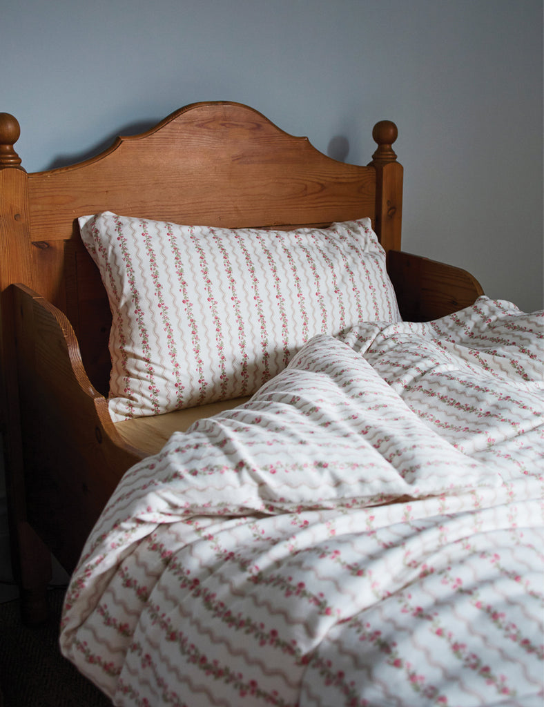 Bed with wooden headboard and floral-patterned bedding against a gray wall
