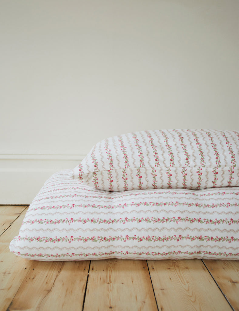 Textured bedspread with red patterns on a wooden floor against a white wall