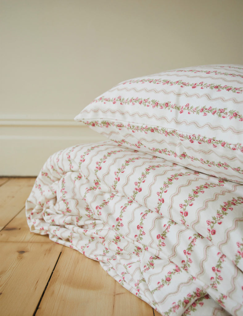 Floral patterned bedding on a wooden floor with a neutral wall background