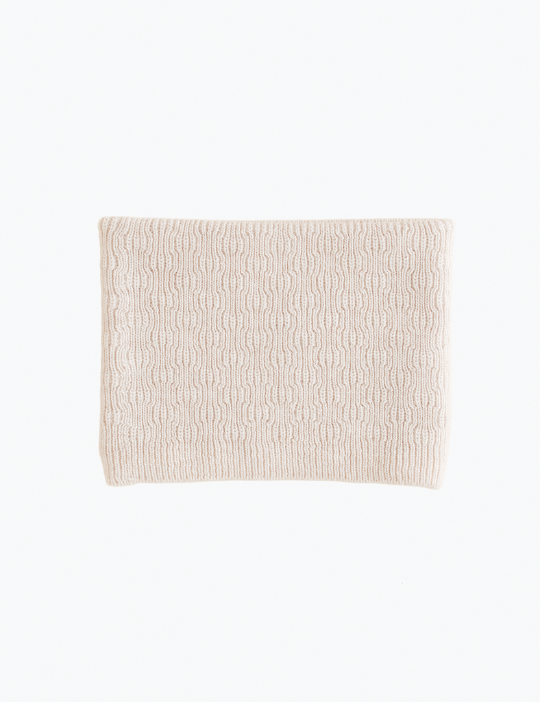 Image of cream colored knitted scarf on a white background.