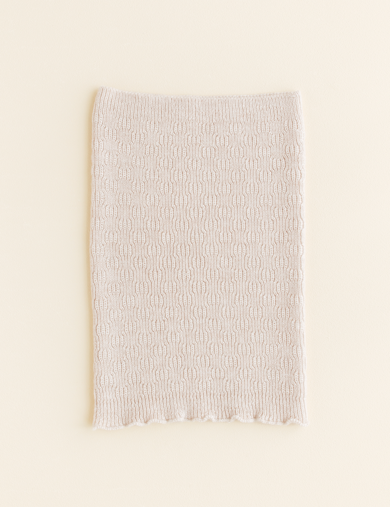 Image of cream colored knitted scarf on a white background.