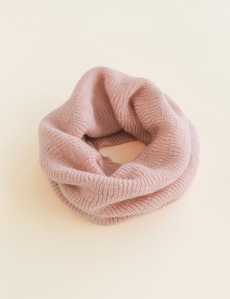 Image of a pink textured knit scarf on a beige background.