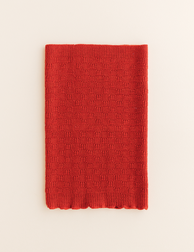 Red knitted tube scarf on a white background.