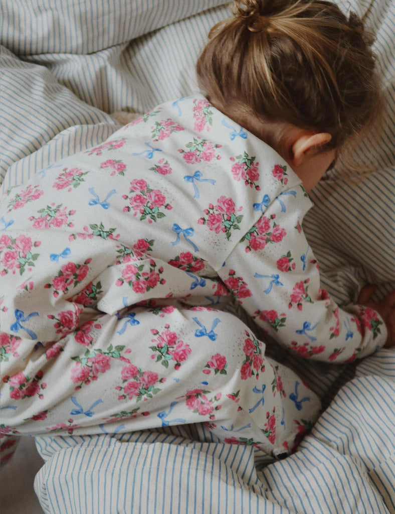 Child wearing a floral outfit lying on a striped surface