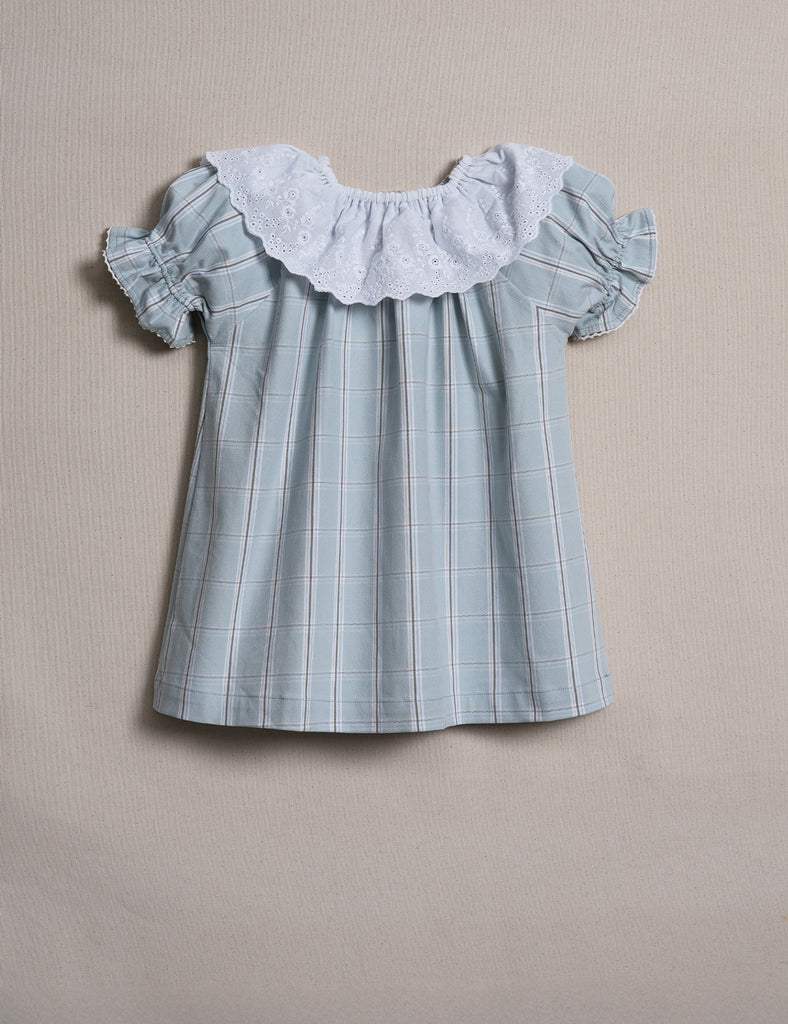Light blue checkered blouse with ruffled sleeves and collar on a beige background