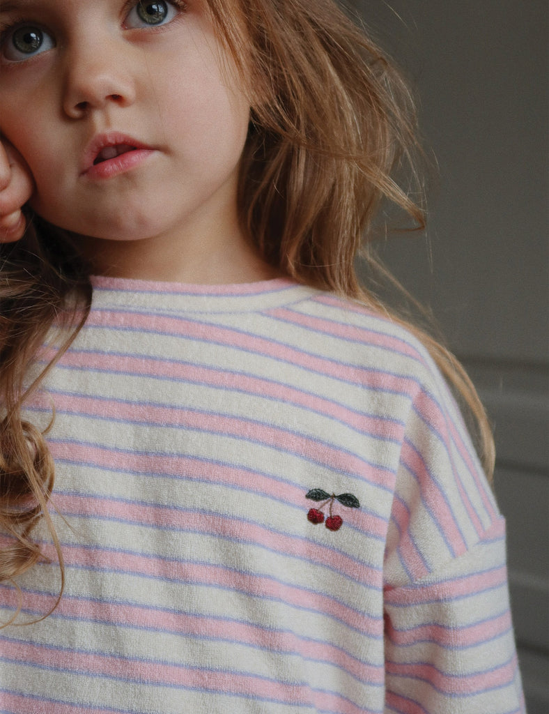 Young girl wearing a striped shirt with a cherry design.