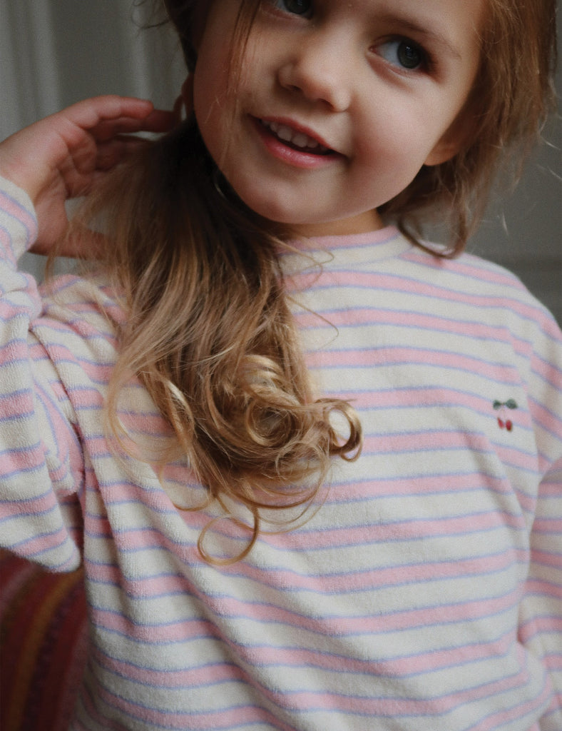 Child wearing a striped shirt with a small design on a plain background