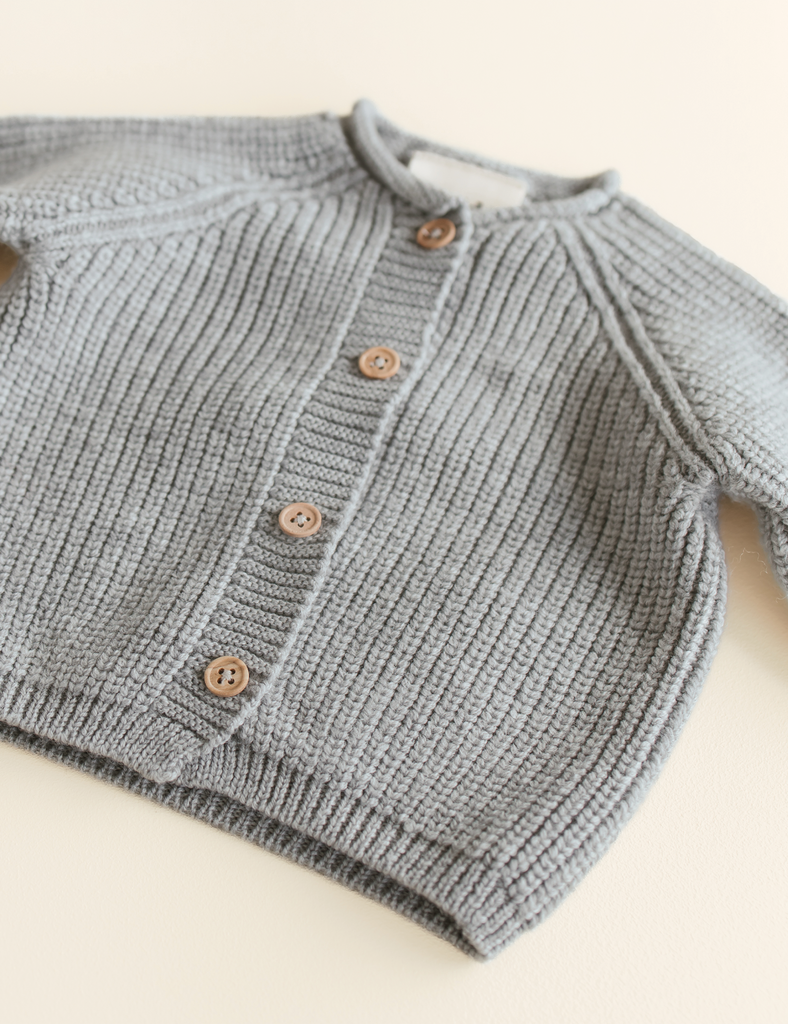 Gray knitted cardigan with wooden buttons on a light background