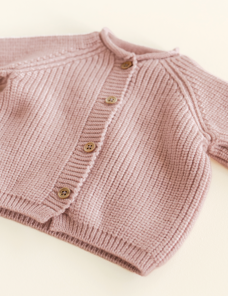 Pink knitted cardigan on a soft white background.