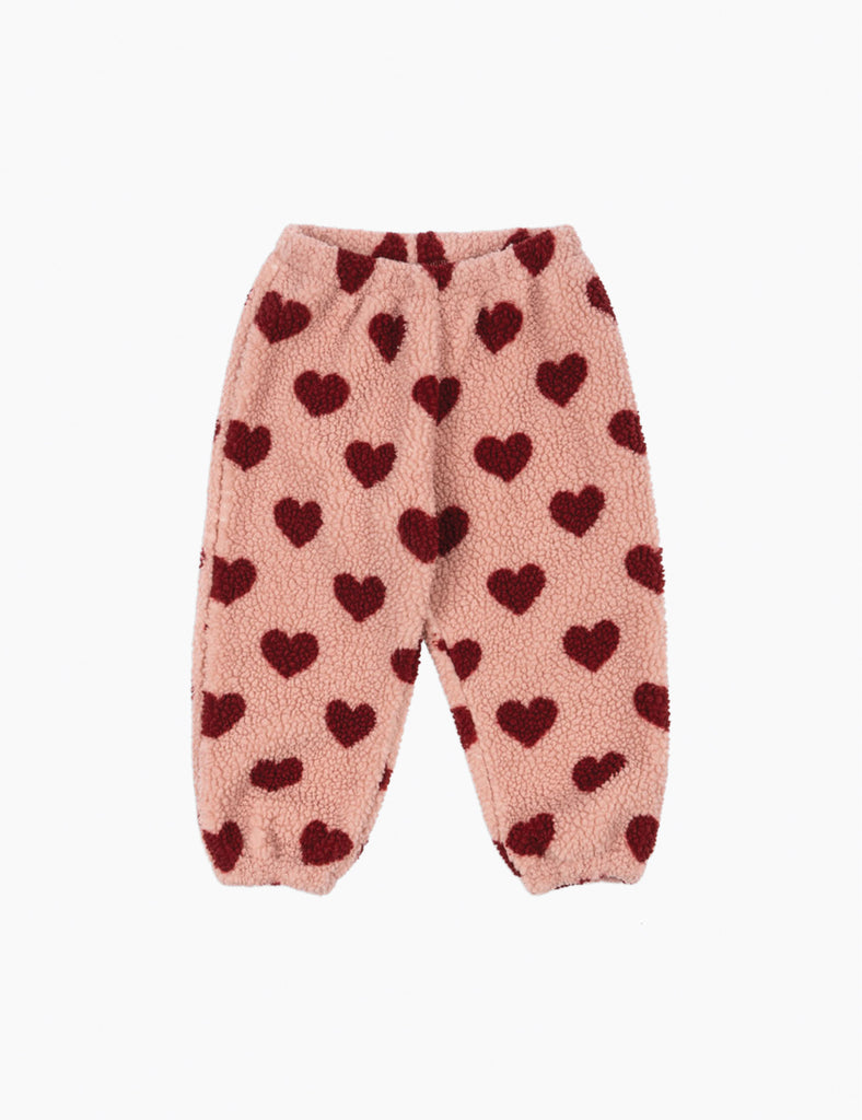 Pink fuzzy pants with red heart patterns on a white background