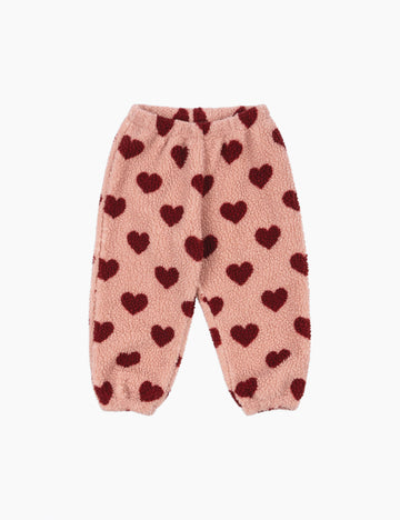 Pink fuzzy pants with red heart patterns on a white background