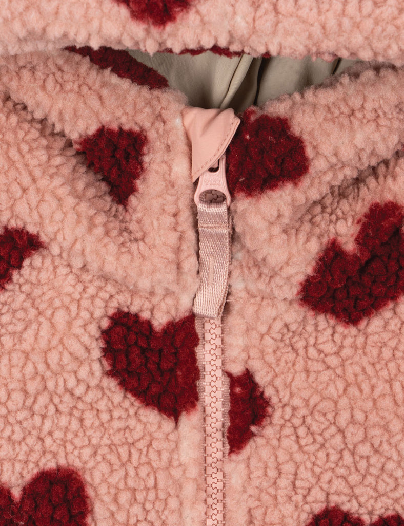 Close-up of a pink fleece jacket with red heart patterns and a zipper.