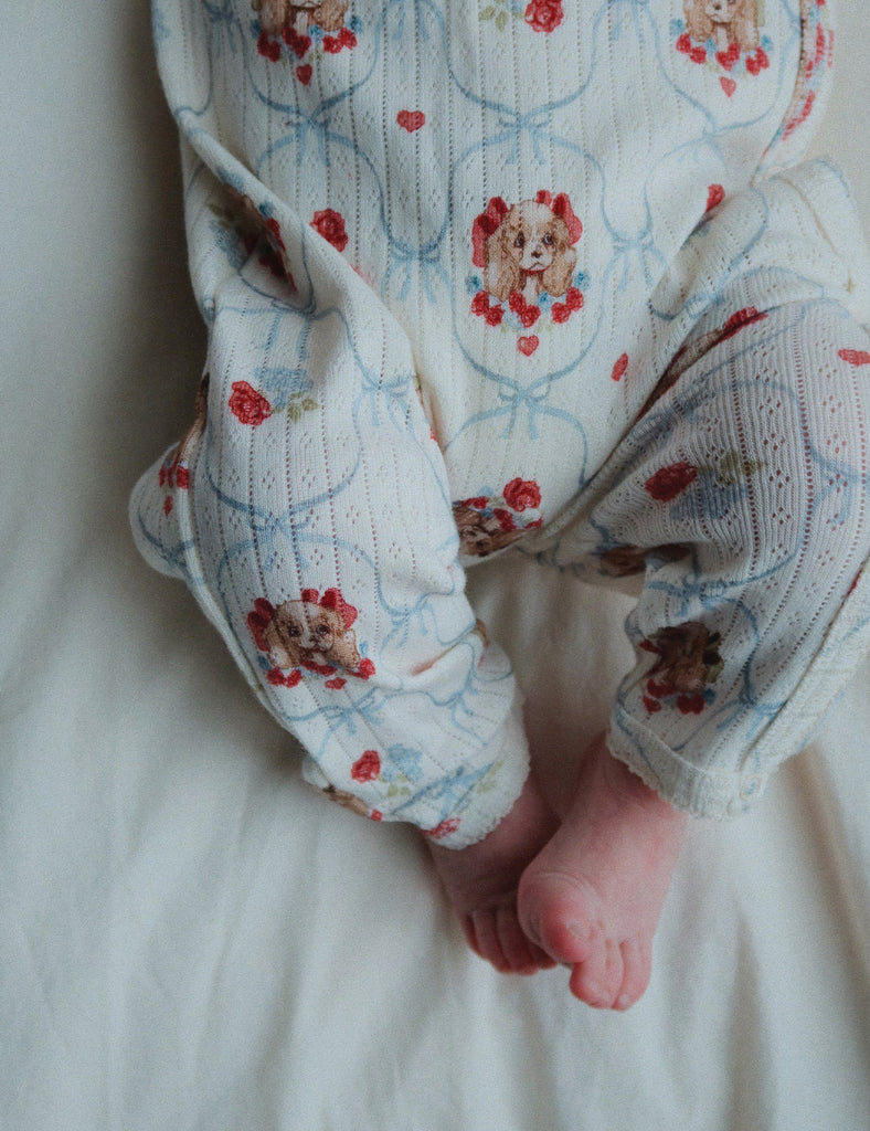 Baby's feet in patterned romper on a white surface