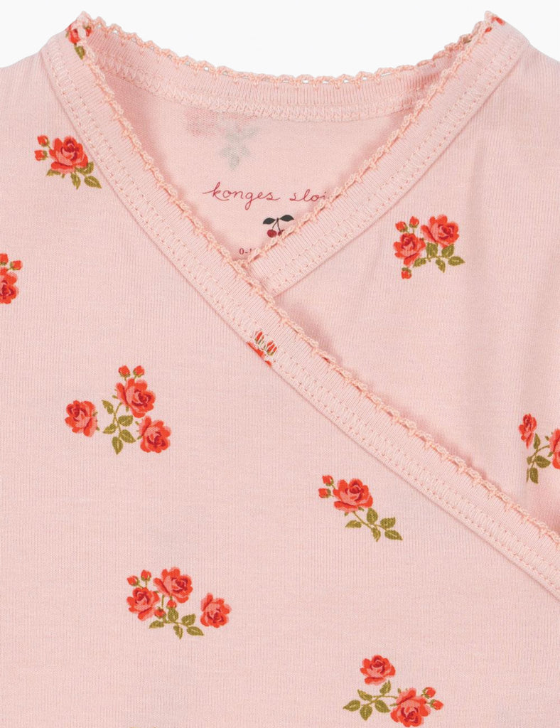 Close-up of a pink garment with floral patterns and 'konges slojd' branding.