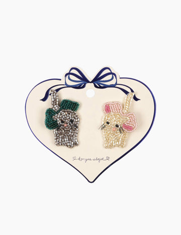 Two decorative hand beaded kitty hair clips on a heart-shaped card with a bow.