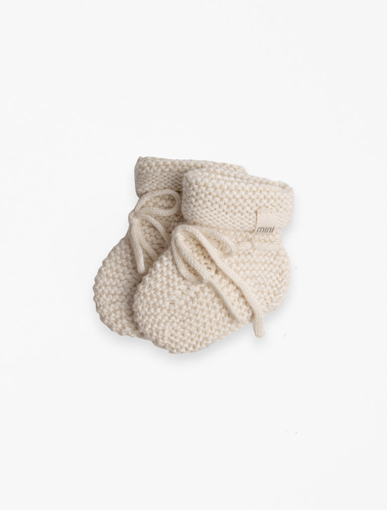 Knitted Booties in Buttercream flat lay image.