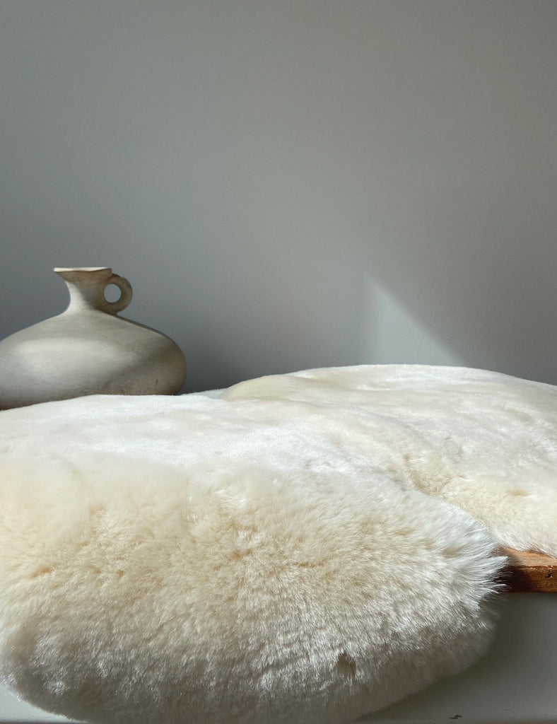 Sheepskin rug with a ceramic vase on a neutral background