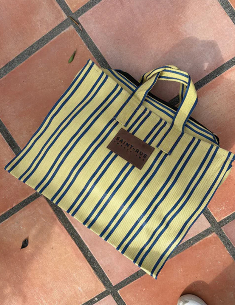 Striped tote bag with a brand label on a tiled floor